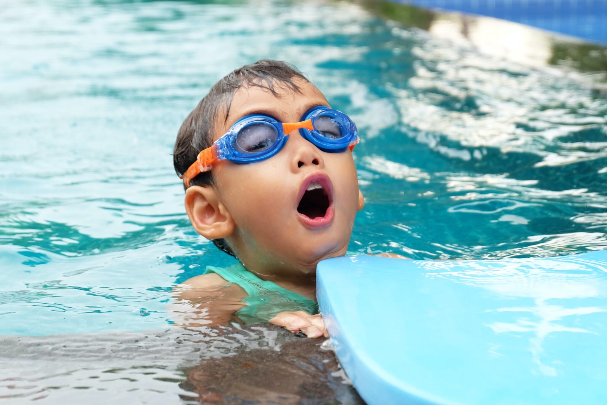 kind im Wasser mit Schwimmbrille holt Luft