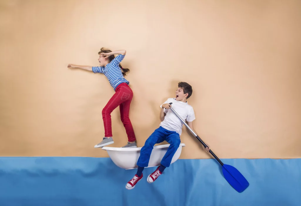 Zwei Kinder segeln auf einem Boot. Das Bild soll verdeutlichen, dass das Erlernen des Schwimmens, ein Sprungbrett für andere Wasser Sportarten sein kann.