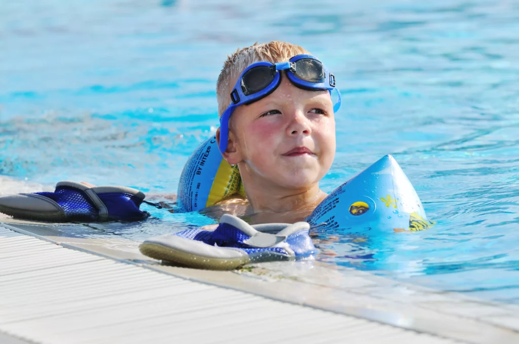 Kind schwimmt mit Schwimmflügeln, die wir zum Schwimmenlernen nicht empfehlen.