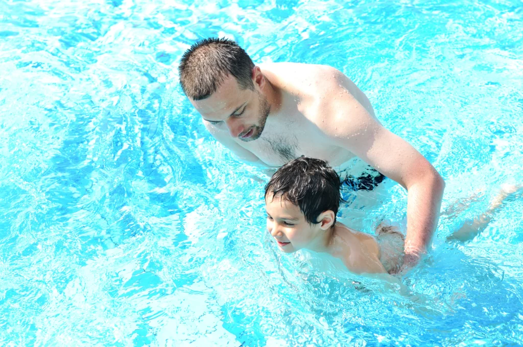 Vater mit Kind im Wasser beim Schwimmenlernen