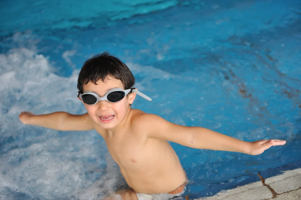 Kind, das mit Schwimmbrille offensichtlich Angst vor dem Wasser hat